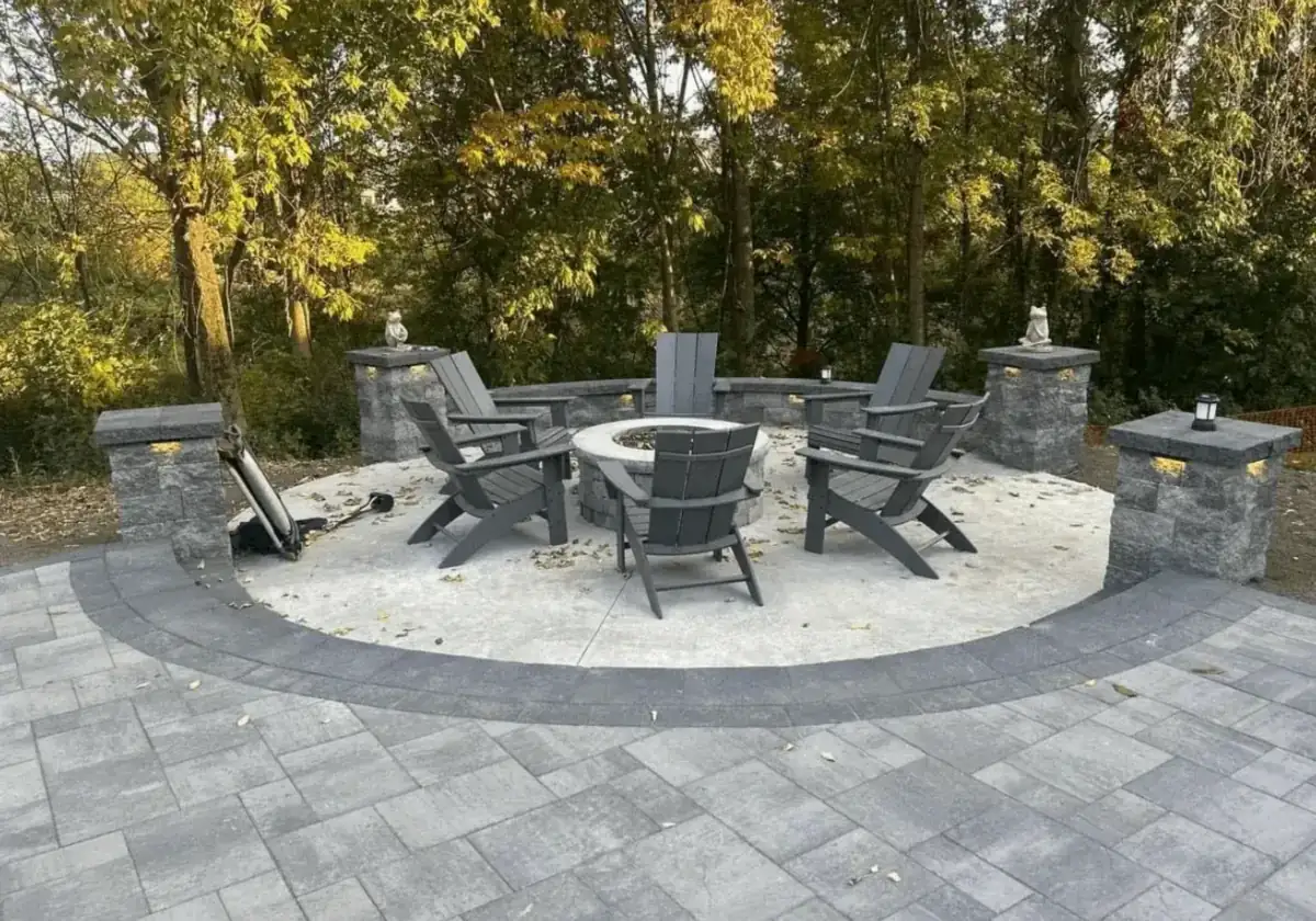 Circular concrete fire pit patio with block seat walls, lighted columns and a paver surround built by Cornerstone Concrete of WNY