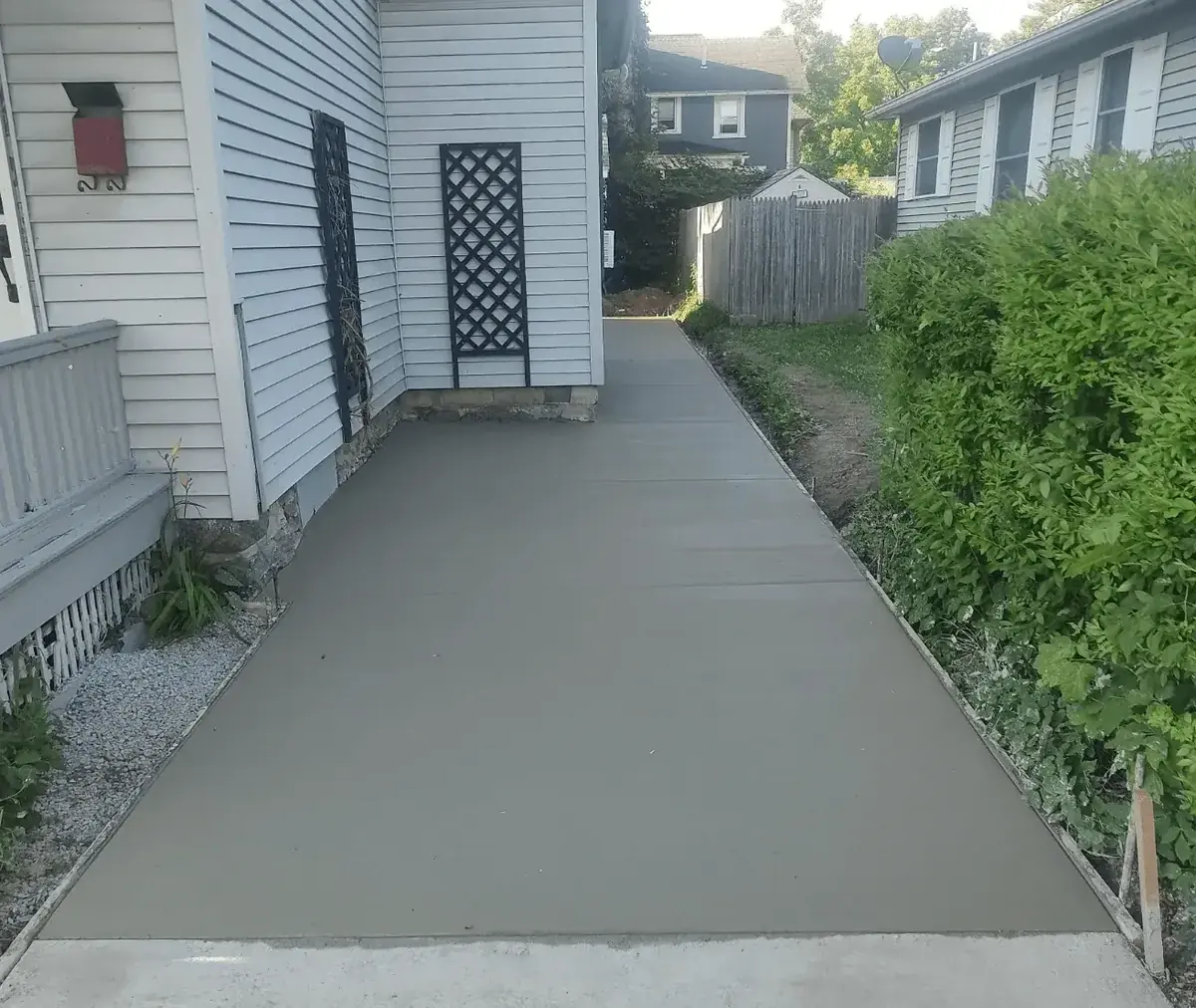 Wide concrete walkway poured along the side of a home in East Aurora NY by Cornerstone Concrete of WNY