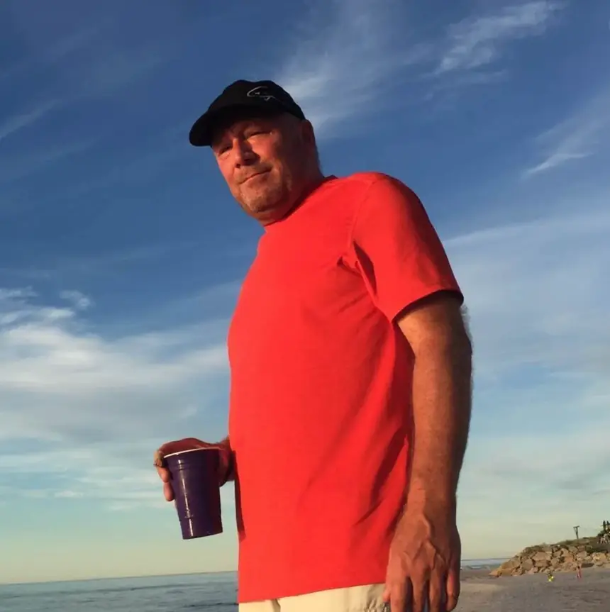 Jim "Clapper" Clapp, owner of Cornerstone Concrete of WNY, on the beach in a red shirt and cap